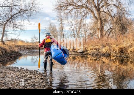 Senior Paddler startet sein aufblasbares Packraft auf einem Fluss im Frühjahr - Poudre Fluss im Norden Colorado Stockfoto