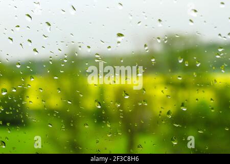 Regen Tröpfchen auf einem Fenster Glas, verschwommen Frühling Landschaft Hintergrund Stockfoto