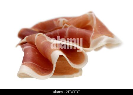 In Scheiben geschnitten aus Jamon Serrano, spanischer trockengehauter Schinken. Gefaltete Schinken-Scheibe isoliert auf weißem Hintergrund Stockfoto