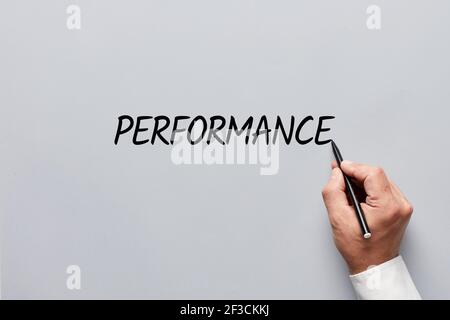 Männliche Hand schreibt das Wort Performance auf grauem Hintergrund. Beurteilung des Konzepts für die Arbeit, die Arbeit oder die Unternehmensleistung. Stockfoto