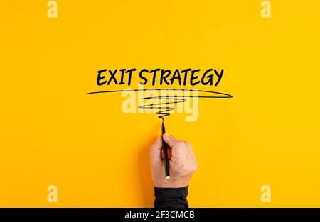 Männliche Hand schreiben Ausstiegsstrategie auf gelbem Hintergrund. Business-Exit-Strategieplan oder Managementkonzept. Stockfoto