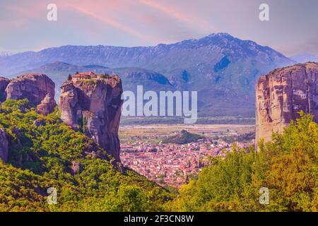 Meteora, Griechenland, Kloster der Heiligen Dreifaltigkeit auf einem Felsen und Kalampaka Stadt im Tal, Blick auf den Sonnenuntergang Stockfoto