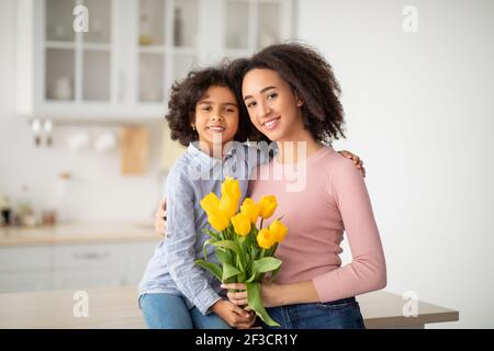 Schwarzes Mädchen feiert Muttertag, Gruß Frau mit Tulpen Stockfoto