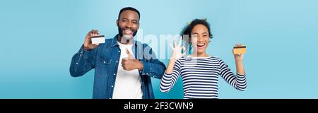 Aufgeregt afroamerikanischen Paar mit Kreditkarten und zeigt wie und okay Gesten auf blau, Banner Stockfoto