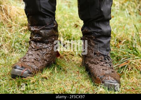 Nahaufnahme der Wanderschuhe. Mann, Wanderer mit schlammigen Wanderschuhen und wasserdichten Gamaschen in Wales, Großbritannien Stockfoto