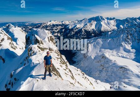 Bergsteiger beim Blick auf eine verschneite Berglandschaft an einem sonnigen Wintertag. Stockfoto