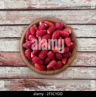 Frische Erdbeeren lagen auf rustikalem Hintergrund. Draufsicht. Hintergrund von Waldbeeren. Reife wilde Erdbeere auf einem hölzernen Hintergrund. Wilde Erdbeeren mit Stockfoto