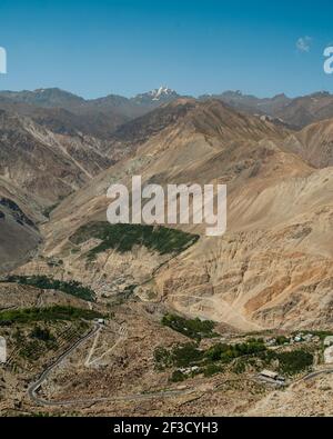 Blick über den Spiti Tal mit Blick auf die Gipfel des Himalaya, ein kleines Dorf und Oase der Bäume von Nako, Himachal Pradesh, Indien gesehen. Stockfoto