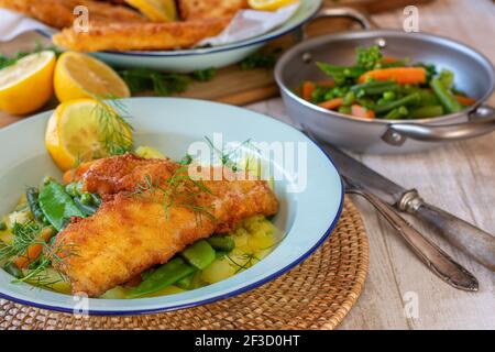 Panierter Fisch mit Gemüse und Kartoffeln auf einem Teller Stockfoto