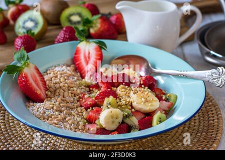 Müsli mit frischen Früchten und gerösteten Nüssen in einer Schüssel Auf Küchentisch Stockfoto