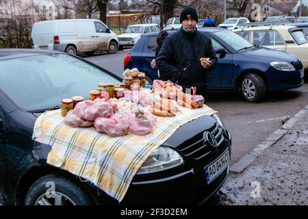 UZHHOROD, UKRAINE - 14. MÄRZ 2021 - EIN Mann verkauft hausgemachte Produkte auf der Motorhaube eines Autos auf dem Sonntag Flohmarkt in der Radvanka Nachbarn angeordnet Stockfoto