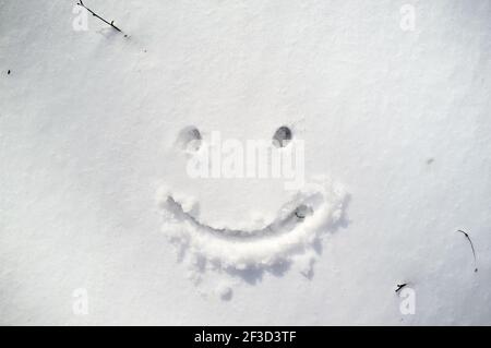 Nettes Smiley Gesicht gezeichnet auf Schnee im Wintertag. Stockfoto