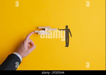 Konzeptuelles Bild von Teamarbeit und Problemlösung mit männlicher Hand und Silhouetten männliche Figur Anordnung Holzblöcke. Stockfoto