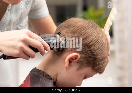 Junge Mutter Friseur schneidet ihr Baby Junge zu Hause mit Haarschneider während Quarantäne. Selektiver Fokus. Porträt Stockfoto