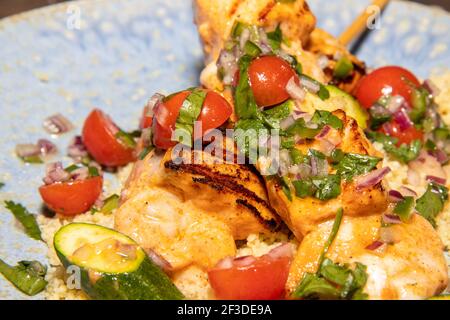 Ein köstlicher Teller mit Frühlingslachs und Garnelen Spieße mit Couscous Salat und Zitrusfrüchte Salsa Stockfoto