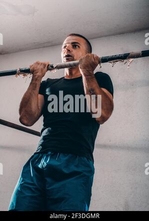 Crossfit Mann, Pull-ups auf Klimmzugstange. Portrait des jungen Mannes Cross Training Arme auf horizontale Balken auf Fitnessbereich im Freien im Sommer Stockfoto