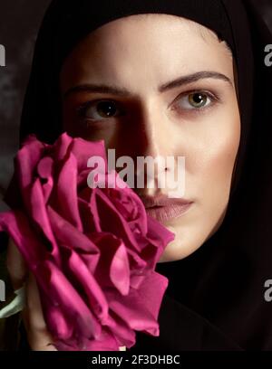 Künstlerisches Atelierportrait mit roten Rosen der Ekstase Eine zeitgemäße Nonne Stockfoto