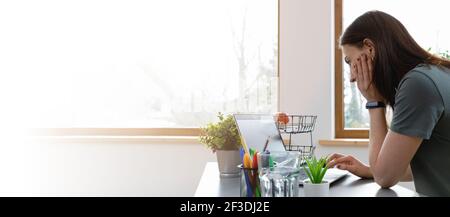 Frauen arbeiten auf einem Laptop zu Hause im Büro auf dem Dachboden. Banner mit Kopierbereich. Stockfoto