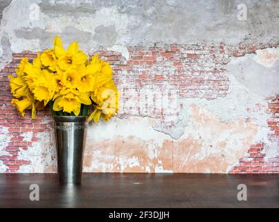 Ein Strauß Narzissen in einer Vase gegen rustikale birckwand mit Kopierraum. Stockfoto