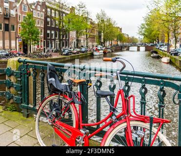 Rotes Fahrrad auf einer Brücke in Amsterdam in Holland in Niederlande Stockfoto
