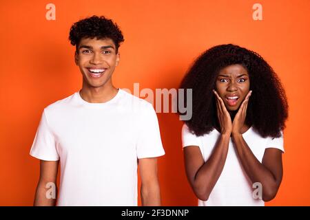 Foto von jungen afro paar Freund lächelnd und unglückliche Freundin Halten Sie Hände Wangen isoliert auf orangefarbenem Hintergrund Stockfoto