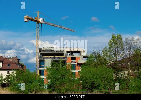 Bau Turmdrehkran auf dem Hintergrund des Gebäudes ein Haus. Kran in der Nähe des Gebäudes auf dem Hintergrund des bewölkten Himmels Stockfoto