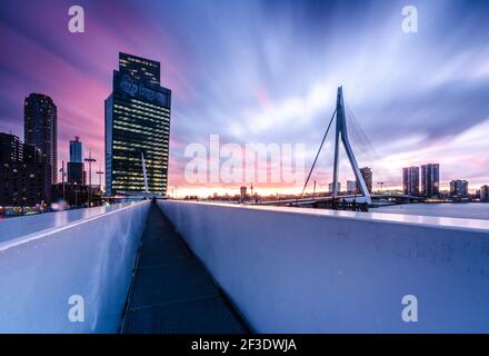Malerischer, violetter Sonnenuntergang über der modernen Erasmus-Brücke in Rotterdam, Niederlande. Modernes Stadtpanorama. Stockfoto