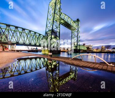 Historische Eisenbahntrassebrücke mit angehobener Mittelstrecke am frühen Abend. Spiegelung in der Pfütze. Koningshaven-Brücke in Rotterdam, Niederlande. Stockfoto