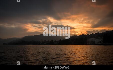 Goldener Sonnenaufgang/Sonnenuntergang hinter Wolken. Spiegelung der Dämmerungsfarbe auf der Wasseroberfläche des Sees. Wolkiger Himmel. Stockfoto