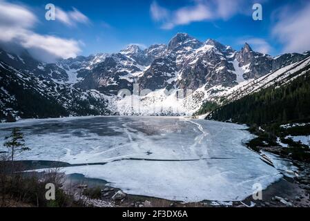 Panorama Winter Berglandschaft Foto. Zerklüftete Felskrippe über gefrorener Seenoberfläche. Auge des Meeres (Morskie oko) See in der Tatra Berge. Stockfoto