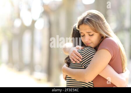 Bedauert Frau umarmt einen Freund versöhnend auf der Straße Stockfoto