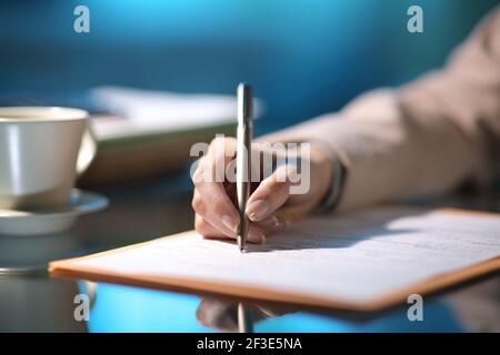 Nahaufnahme eines Unternehmers Hand Ausfüllen Formular in Die Nacht im Büro Stockfoto