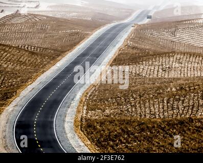 Desert Highway.die Taklamakan Wüste liegt in der Mitte des Tarim Basin. 'Takla Makan' in uigurischer Sprache bedeutet 'man kann es aber hinbekommen Stockfoto