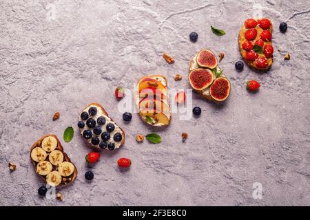 Hausgemachter Sommertoast mit Frischkäse, Nussbutter und Früchten und Beeren, Draufsicht. Stockfoto