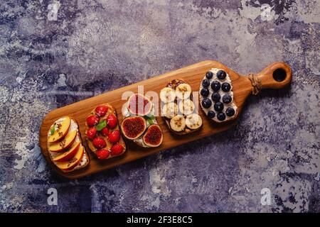 Hausgemachter Sommertoast mit Frischkäse, Nussbutter und Früchten und Beeren, Draufsicht. Stockfoto