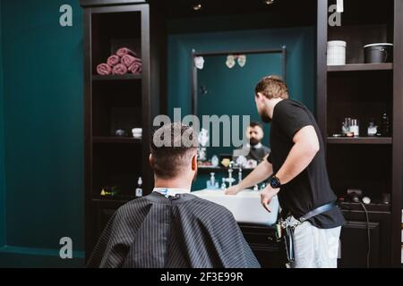 Friseur macht Haarschnitt zu männlichen Kunden, Prozess der Bedienung Besucher in Friseursalon. Stockfoto