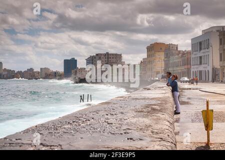 Havanna, Kuba - 23. März 2010: Ein Mann und eine Frau, als Paar, beobachten das raue Meer an einem windigen Tag, von der Malecon Promenade, in der Nähe des Antonio Mace Stockfoto