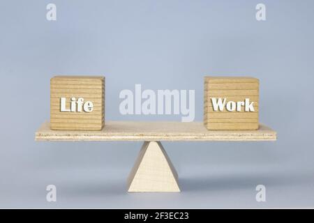 Die Holzskala zeigt die Balance mit Holzblöcken 'Life' Und 'Arbeit' auf dem blauen Hintergrund Stockfoto