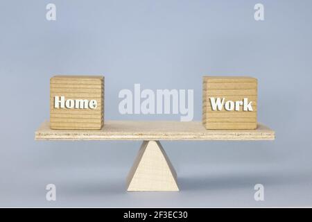 Die Holzskala zeigt die Balance mit Holzblöcken 'Home' Und 'Arbeit' auf dem blauen Hintergrund Stockfoto