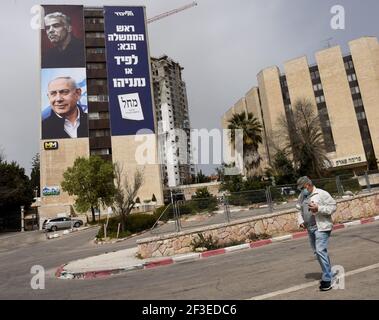 Jerusalem, Israel. März 2021, 15th. Ein Mann geht am Montag, dem 15. März 2021, an einem Wahlbanner für die Likud-Partei vorbei, mit ihrem Führer, Premierminister Benjamin Netanjahu (unten) und Oppositionsführer Yair Lapid (oben} auf einem Gebäude in Jerusalem). Netanjahu steht vor seiner vierten Wiederwahl seit zwei Jahren, als Israelis am 23. März an die Urnen gehen. Foto von Debbie Hill/UPI Kredit: UPI/Alamy Live Nachrichten Stockfoto