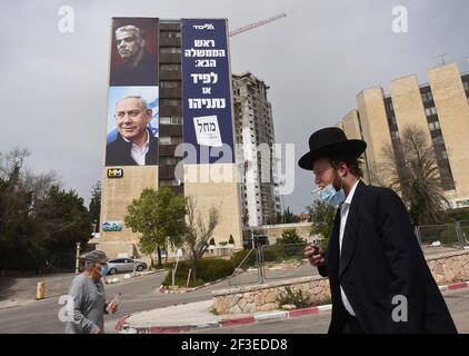 Jerusalem, Israel. März 2021, 15th. Ein ultra-orthodoxer Jude kommt am Montag, den 15. März 2021, an einem Wahlbanner für die Likud-Partei vorbei, zusammen mit ihrem Führer, Premierminister Benjamin Netanjahu (unten) und Oppositionsführer Yair Lapid (oben} auf einem Gebäude in Jerusalem). Netanjahu steht vor seiner vierten Wiederwahl seit zwei Jahren, als Israelis am 23. März an die Urnen gehen. Foto von Debbie Hill/UPI Kredit: UPI/Alamy Live Nachrichten Stockfoto