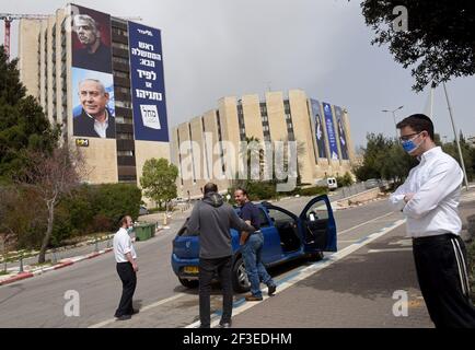 Jerusalem, Israel. März 2021, 15th. Israelis stehen auf der Straße in der Nähe eines Wahlbanners für die Likud-Partei mit ihrem Führer Premierminister Benjamin Netanjahu (unten) und Oppositionsführer Yair Lapid (oben} auf einem Gebäude in Jerusalem am Montag, 15. März 2021. Netanjahu steht vor seiner vierten Wiederwahl seit zwei Jahren, als Israelis am 23. März an die Urnen gehen. Foto von Debbie Hill/UPI Kredit: UPI/Alamy Live Nachrichten Stockfoto