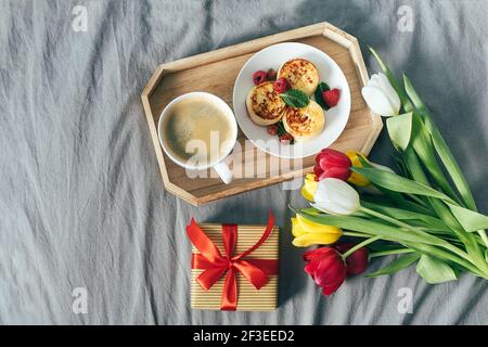 Blick von oben auf den Urlaub Frühstück auf dem Bett. Muttertag, 8. märz, valentinstag Konzept. Köstliche Filiale - Kaffee, Quark, Pfannkuchen, Geschenkbox und Stockfoto