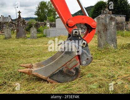 Ein Bagger zum Graben eines Grabes auf einem Friedhof zur Begräbnis oder Exhumierung. Stockfoto