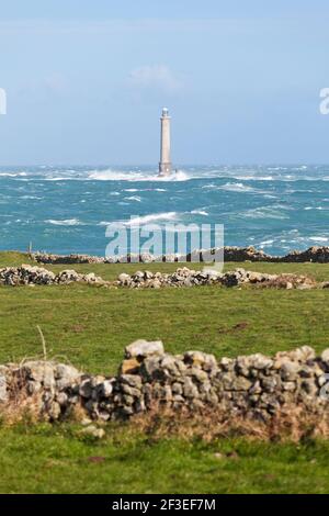 Der Leuchtturm am Cap de la Hague in einem stürmischen Meer, vor alten Steinmauern. Stockfoto