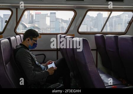 Hongkong, China. März 2021, 16th. Ein Mann mit Gesichtsmaske als Vorsichtsmaßnahme gegen die Ausbreitung des Coronavirus benutzt einen Nintendo Switch, als er auf einer Fähre den Victoria Harbour überquert. Eine Reihe neuer Coronavirus-Fälle (COVID-19) traten bei großen Banken und Anwaltskanzleien im Central District, dem Geschäftszentrum der Stadt, auf, als Hongkong eine Spitze von neuen Infektionen meldete. Kredit: SOPA Images Limited/Alamy Live Nachrichten Stockfoto