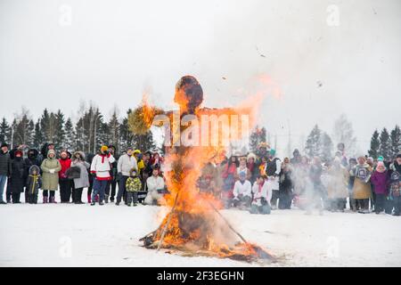 Wologda, Russland - 13. März 2021: Feiertag der Fasching in Russland. Große Puppe brennt. Die Leute beobachten Stockfoto