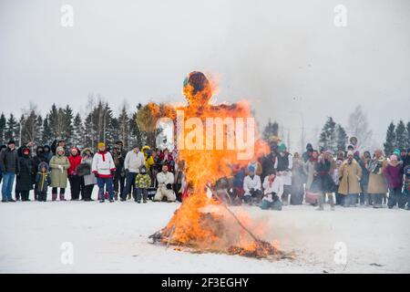 Wologda, Russland - 13. März 2021: Feiertag der Fasching in Russland. Große Puppe brennt. Die Leute beobachten Stockfoto