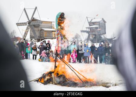 Wologda, Russland - 13. März 2021: Feiertag der Fasching in Russland. Große Puppe brennt. Die Leute beobachten Stockfoto