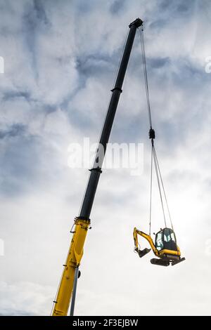 Hydraulischer Kran Teleskopausleger Detail bewegte Spur Bagger auf bewölktem Himmel Hintergrund. Gelber Jib der mobilen Fahrzeug Hebegerät trägt Erdbeweger. Stockfoto